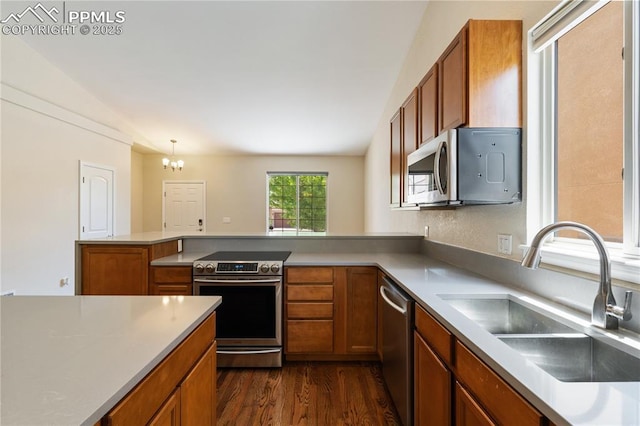 4410 Campus Bluffs Ct, Colorado Springs, CO 80918 - kitchen with stainless steel appliances, brown cabinetry, a peninsula, a chandelier, and dark wood finished floors