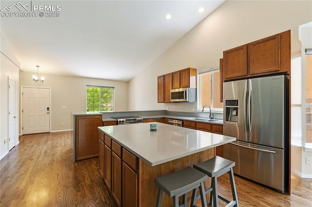 4410 Campus Bluffs Ct, Colorado Springs, CO 80918 - kitchen featuring appliances with stainless steel finishes, a peninsula, lofted ceiling, dark wood-type flooring, and brown cabinets