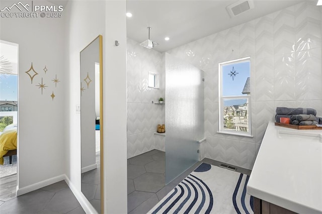 10423 Bergan Peak Ct, Colorado Springs, CO 80924 - ensuite bathroom with a walk in shower, healthy amount of natural light, recessed lighting, tile patterned flooring, and tile walls
