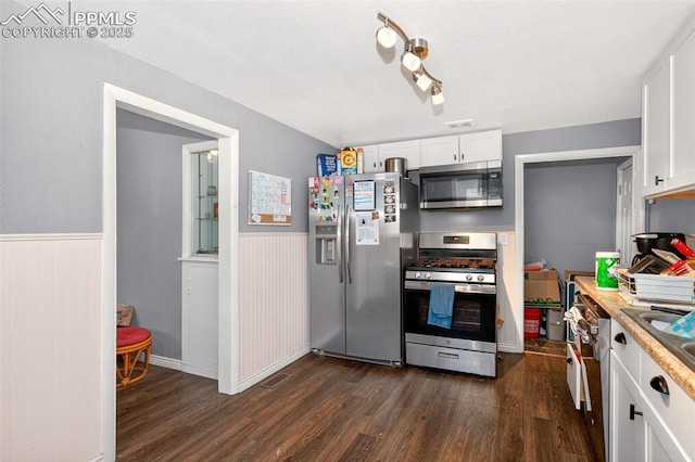 1301 Cypress St, Pueblo, CO 81004 - kitchen with appliances with stainless steel finishes, dark wood finished floors, a wainscoted wall, and white cabinets