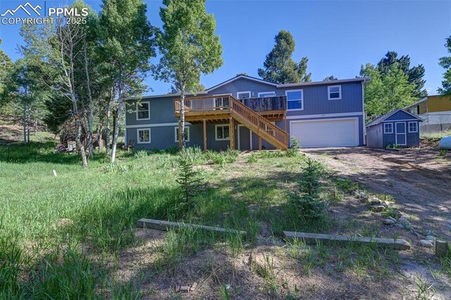 451 Fern Rd, Woodland Park, CO 80863 - back of property with dirt driveway, a deck, a garage, stairs, and a storage unit