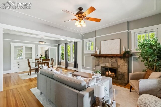 1326 E Platte Ave, Colorado Springs, CO 80909 - living area featuring a stone fireplace, light wood-style flooring, and a ceiling fan