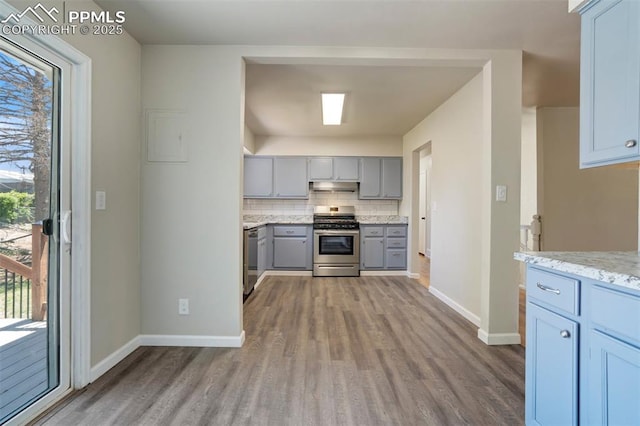 4116 Fitzpatrick Dr, Colorado Springs, CO 80909 - kitchen featuring stainless steel appliances, under cabinet range hood, gray cabinetry, wood finished floors, and tasteful backsplash