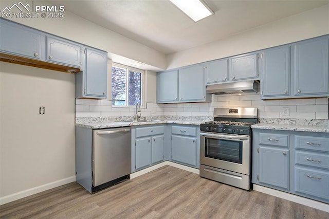 4116 Fitzpatrick Dr, Colorado Springs, CO 80909 - kitchen featuring appliances with stainless steel finishes, under cabinet range hood, blue cabinets, and backsplash