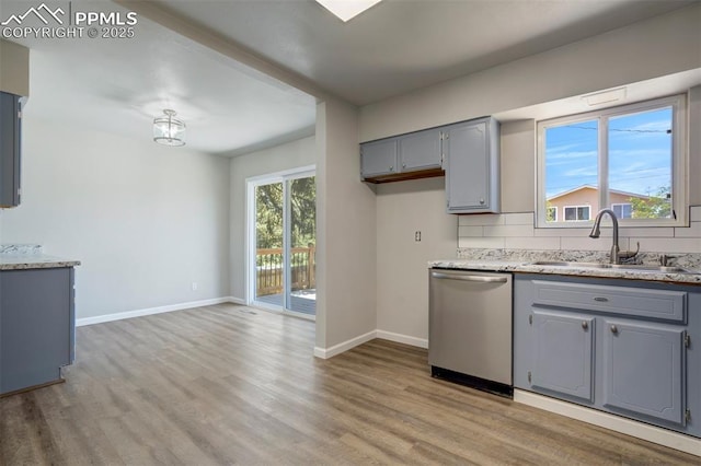 4116 Fitzpatrick Dr, Colorado Springs, CO 80909 - kitchen with dishwasher, gray cabinetry, light wood finished floors, decorative backsplash, and light stone counters