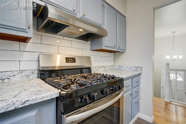 4116 Fitzpatrick Dr, Colorado Springs, CO 80909 - kitchen with stainless steel range with gas cooktop, under cabinet range hood, gray cabinetry, wood finished floors, and tasteful backsplash