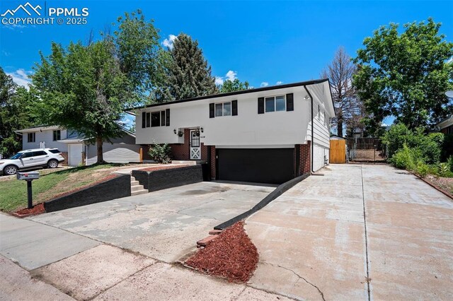 4116 Fitzpatrick Dr, Colorado Springs, CO 80909 - split foyer home featuring brick siding, concrete driveway, a garage, and stucco siding