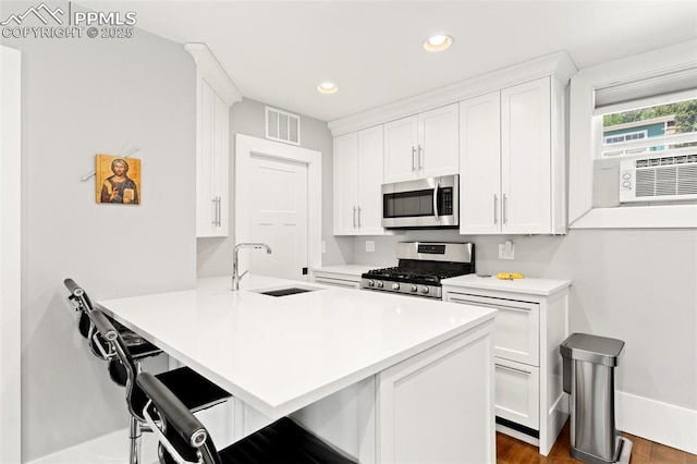 112 N 12th St, Colorado Springs, CO 80904 - kitchen featuring appliances with stainless steel finishes, a kitchen bar, white cabinets, and recessed lighting