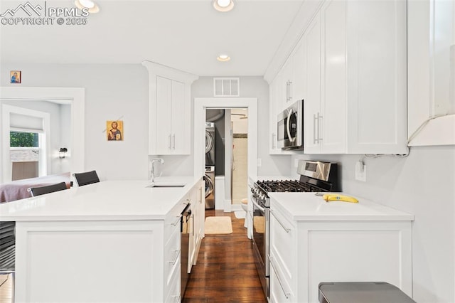 112 N 12th St, Colorado Springs, CO 80904 - kitchen with appliances with stainless steel finishes, stacked washer / drying machine, recessed lighting, light countertops, and dark wood-style floors