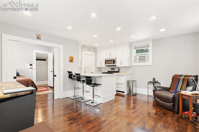 112 N 12th St, Colorado Springs, CO 80904 - kitchen with stainless steel microwave, a kitchen breakfast bar, range, white cabinets, and dark wood-style floors
