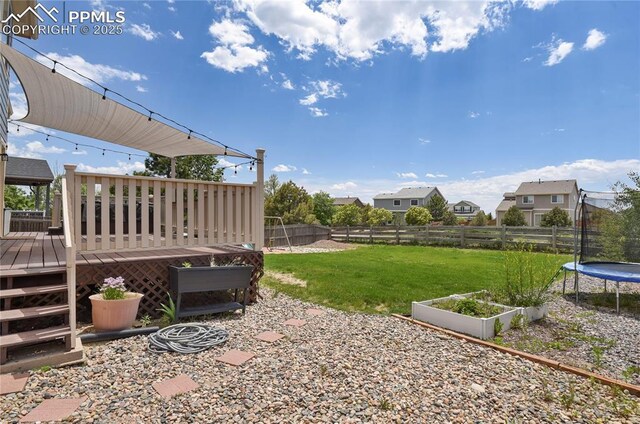 9344 Hirono Rd, Peyton, CO 80831 - fenced backyard with a trampoline, a wooden deck, and a garden