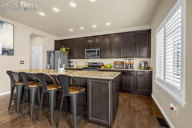 6808 Black Saddle Dr, Colorado Springs, CO 80924 - kitchen featuring appliances with stainless steel finishes, dark wood-style flooring, recessed lighting, a kitchen island with sink, and dark brown cabinets