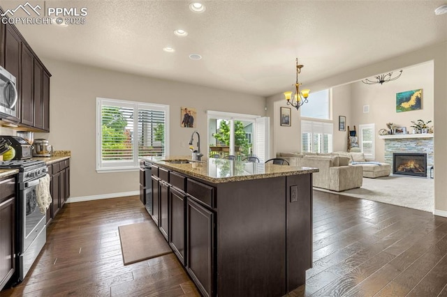 6808 Black Saddle Dr, Colorado Springs, CO 80924 - kitchen with stainless steel appliances, dark wood-type flooring, dark brown cabinets, light stone countertops, and recessed lighting