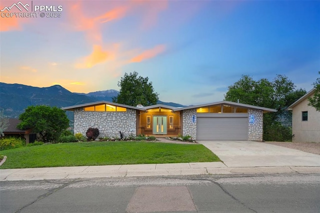 702 Crown Ridge Dr, Colorado Springs, CO 80904 - view of front of property featuring stone siding, an attached garage, a lawn, concrete driveway, and french doors
