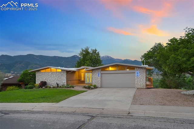 702 Crown Ridge Dr, Colorado Springs, CO 80904 - mid-century home featuring stone siding, a mountain view, a garage, a lawn, and concrete driveway
