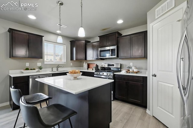 7791 Berwyn Loop, Peyton, CO 80831 - kitchen with appliances with stainless steel finishes, a kitchen breakfast bar, light wood-type flooring, dark brown cabinetry, and recessed lighting