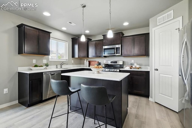 7791 Berwyn Loop, Peyton, CO 80831 - kitchen featuring stainless steel appliances, light wood finished floors, a kitchen bar, dark brown cabinets, and recessed lighting