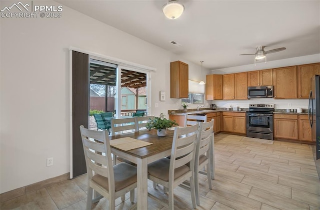 5128 Mountain Air Cir, Colorado Springs, CO 80916 - kitchen featuring appliances with stainless steel finishes, light wood-type flooring, ceiling fan, brown cabinetry, and hanging light fixtures