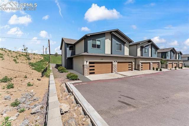 5489 Passport Vw, Colorado Springs, CO 80922 - view of side of home featuring a garage, stone siding, asphalt driveway, and stucco siding