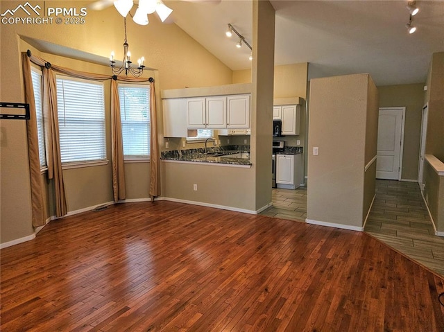 2114 Summerset Dr, Colorado Springs, CO 80920 - kitchen with rail lighting, dark countertops, dark wood-type flooring, white cabinetry, and high vaulted ceiling