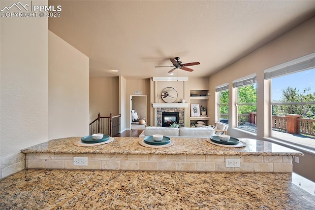 1117 Spectrum Loop, Colorado Springs, CO 80921 - kitchen with a ceiling fan, a fireplace, and light stone countertops