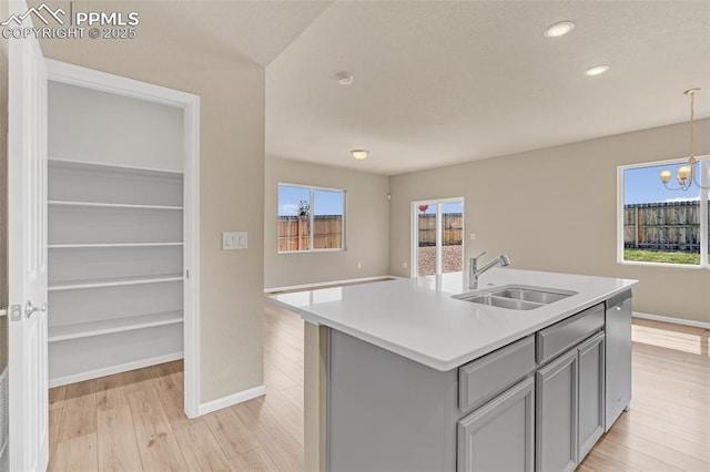 6211 Godwit Ln, Colorado Springs, CO 80925 - kitchen with gray cabinetry, light wood-type flooring, a chandelier, light countertops, and stainless steel dishwasher