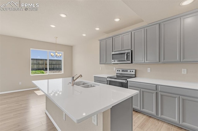 6211 Godwit Ln, Colorado Springs, CO 80925 - kitchen featuring stainless steel appliances, gray cabinets, light wood finished floors, recessed lighting, and an island with sink