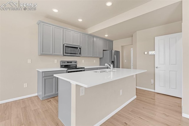6211 Godwit Ln, Colorado Springs, CO 80925 - kitchen with appliances with stainless steel finishes, gray cabinetry, light wood finished floors, an island with sink, and recessed lighting