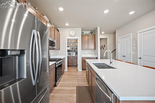 8082 Goldenray Pl, Colorado Springs, CO 80908 - kitchen with stainless steel appliances, an island with sink, light wood finished floors, recessed lighting, and brown cabinets