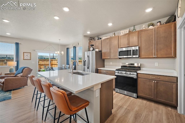 8082 Goldenray Pl, Colorado Springs, CO 80908 - kitchen featuring appliances with stainless steel finishes, light wood-type flooring, a kitchen breakfast bar, open floor plan, and a textured ceiling