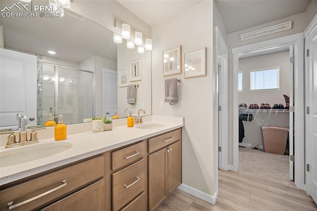 8082 Goldenray Pl, Colorado Springs, CO 80908 - full bathroom featuring double vanity, a stall shower, a spacious closet, and wood finished floors
