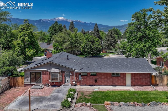 2533 Bennett Ave, Colorado Springs, CO 80909 - view of front of house with brick siding, a mountain view, a chimney, and a shingled roof