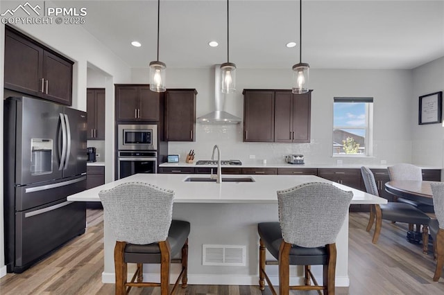 10076 Oro Belle Ct, Colorado Springs, CO 80924 - kitchen featuring appliances with stainless steel finishes, light countertops, decorative backsplash, dark brown cabinets, and a kitchen breakfast bar