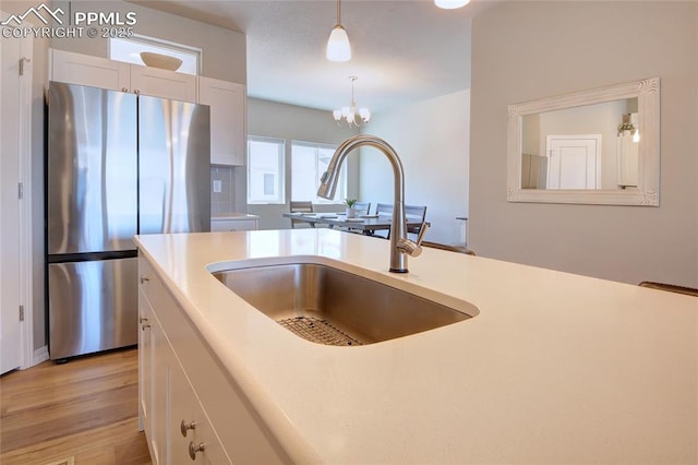 6069 Inman Vw, Colorado Springs, CO 80924 - kitchen featuring freestanding refrigerator, light countertops, pendant lighting, white cabinets, and a chandelier