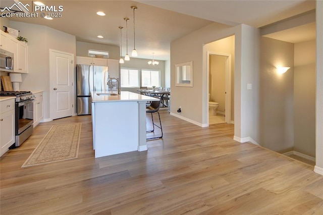 6069 Inman Vw, Colorado Springs, CO 80924 - kitchen with stainless steel appliances, a kitchen breakfast bar, an island with sink, white cabinets, and recessed lighting