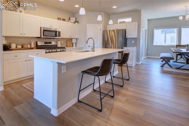 6069 Inman Vw, Colorado Springs, CO 80924 - kitchen with appliances with stainless steel finishes, tasteful backsplash, white cabinetry, a kitchen bar, and a center island with sink