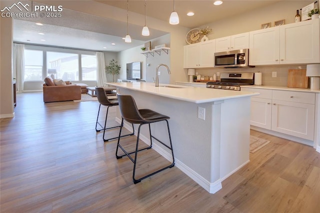 6069 Inman Vw, Colorado Springs, CO 80924 - kitchen with appliances with stainless steel finishes, open floor plan, white cabinets, a breakfast bar area, and backsplash