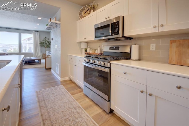 6069 Inman Vw, Colorado Springs, CO 80924 - kitchen featuring appliances with stainless steel finishes, white cabinets, backsplash, light wood-type flooring, and light countertops