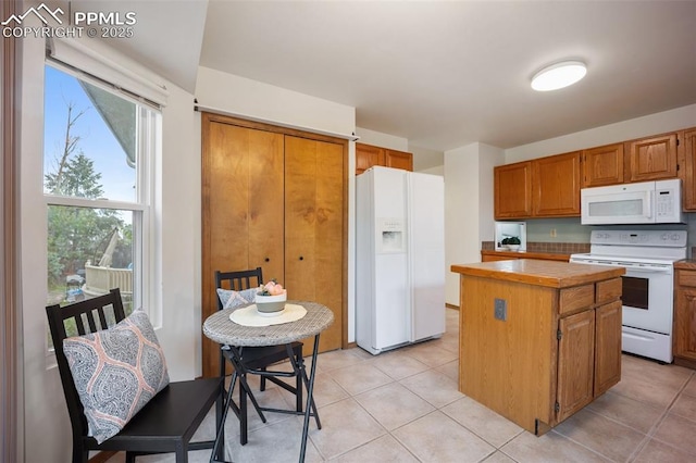2035 Springcrest Rd, Colorado Springs, CO 80920 - kitchen featuring white appliances, a center island, brown cabinets, light tile patterned floors, and light countertops