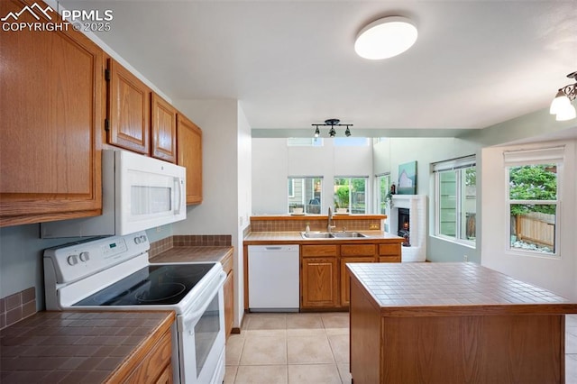 2035 Springcrest Rd, Colorado Springs, CO 80920 - kitchen featuring white appliances, tile counters, a fireplace, brown cabinets, and a peninsula