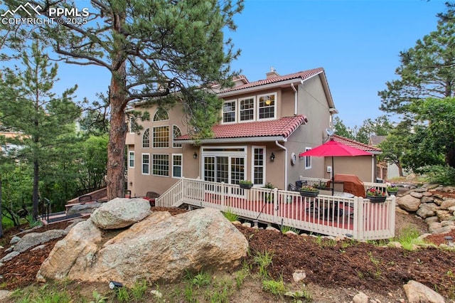 235 Haversham Dr, Colorado Springs, CO 80906 - rear view of property featuring a chimney, a deck, a tiled roof, and stucco siding