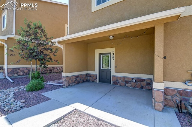 7385 Forest Meadows Ave, Colorado Springs, CO 80908 - view of exterior entry featuring stucco siding, a patio, and stone siding