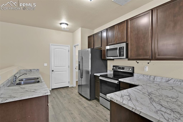 7385 Forest Meadows Ave, Colorado Springs, CO 80908 - kitchen featuring appliances with stainless steel finishes, dark brown cabinets, light wood-type flooring, and light countertops