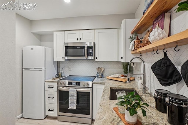 5300 E Cherry Creek Dr Unit 918, Denver, CO 80246 - kitchen featuring stainless steel appliances, open shelves, white cabinets, backsplash, and light stone counters
