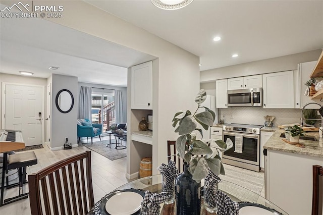 5300 E Cherry Creek Dr Unit 918, Denver, CO 80246 - kitchen with appliances with stainless steel finishes, white cabinets, tasteful backsplash, light stone countertops, and recessed lighting