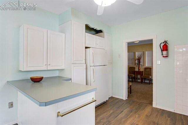 244 Washington St, Monument, CO 80132 - kitchen with freestanding refrigerator, white cabinetry, dark wood finished floors, ceiling fan, and a peninsula