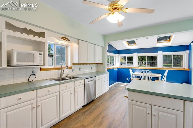 244 Washington St, Monument, CO 80132 - kitchen featuring white microwave, stainless steel dishwasher, white cabinets, and plenty of natural light