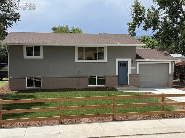 1880 Southmoor Dr, Fountain, CO 80817 - split foyer home with a fenced front yard, an attached garage, brick siding, roof with shingles, and stucco siding