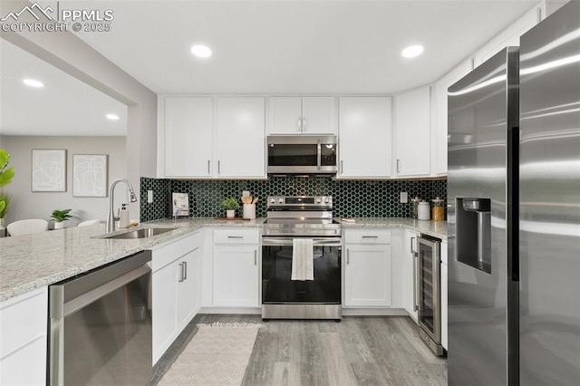 1880 Southmoor Dr, Fountain, CO 80817 - kitchen featuring stainless steel appliances, light wood-style floors, tasteful backsplash, light stone counters, and recessed lighting