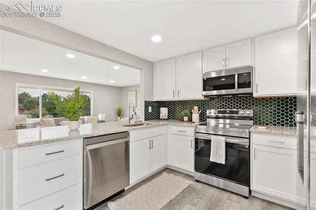 1880 Southmoor Dr, Fountain, CO 80817 - kitchen featuring stainless steel appliances, a peninsula, white cabinets, decorative backsplash, and recessed lighting
